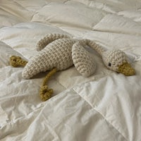 a crocheted swan laying on a bed