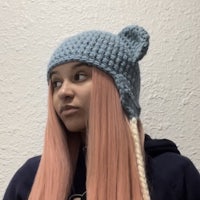 a girl with pink hair wearing a crocheted bear hat